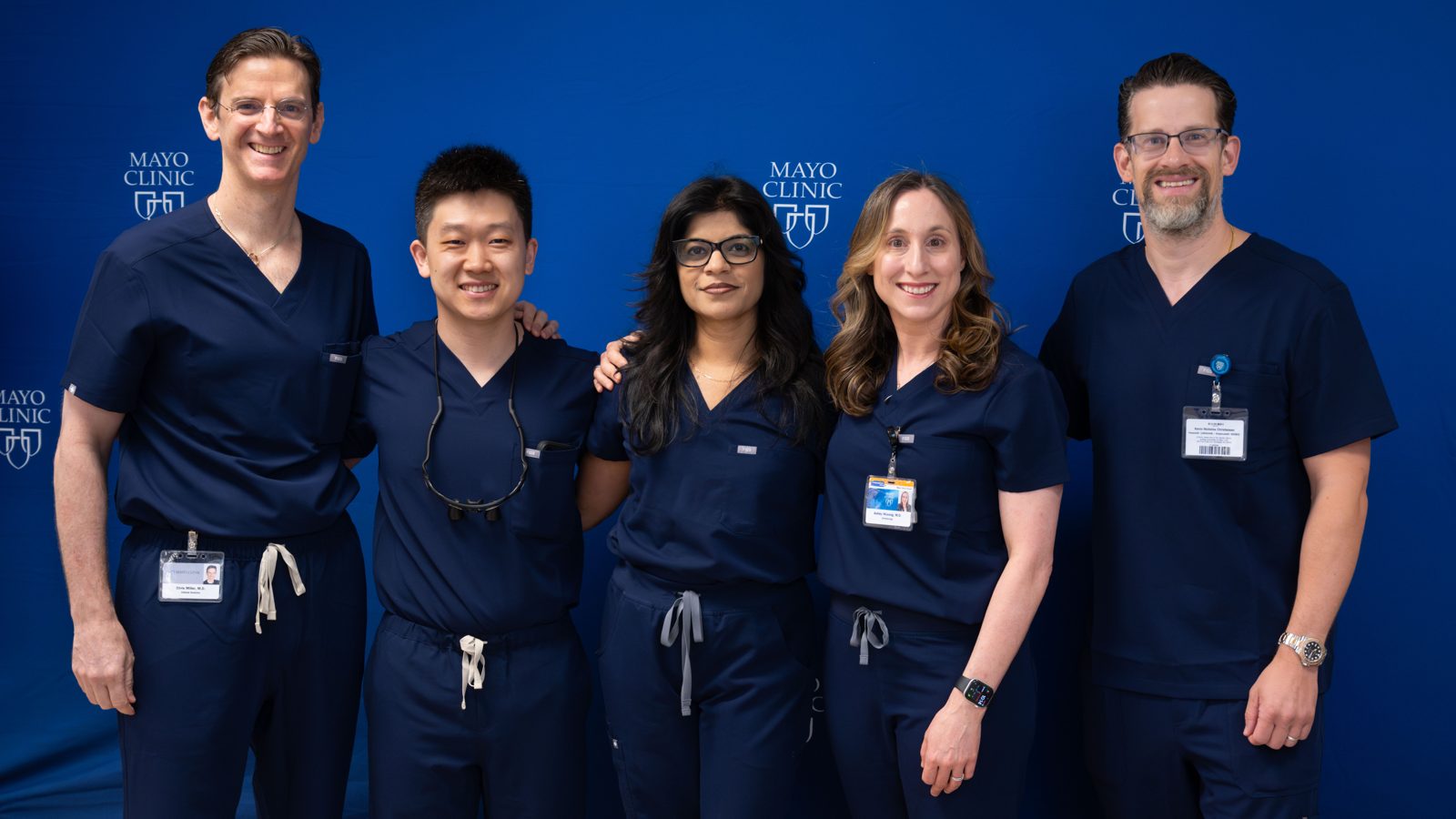 The five course faculty members in navy surgical scrubs standing together in front of a Mayo Clinic backdrop.
