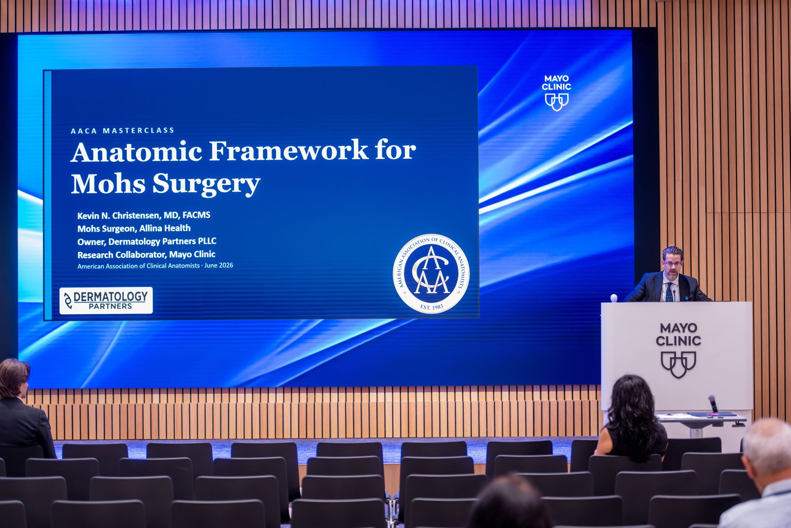 Wide view of the auditorium at Mayo Clinic showing Dr. Christensen at the podium and the title slide reading 'Anatomic Framework for Mohs Surgery'.