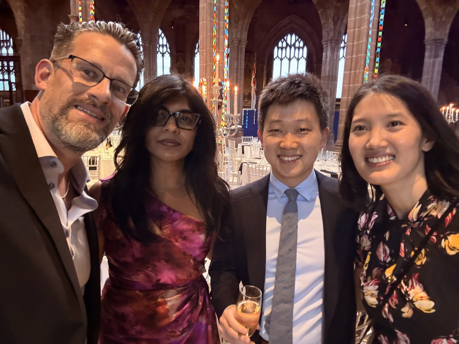 Dr. Kevin Christensen, Dr. Nirusha Lachman, Dr. Jun Zhang, and Dr. Iris Tien-Lynn Lee smiling together inside Manchester Cathedral during the BAD Presidents' Reception.
