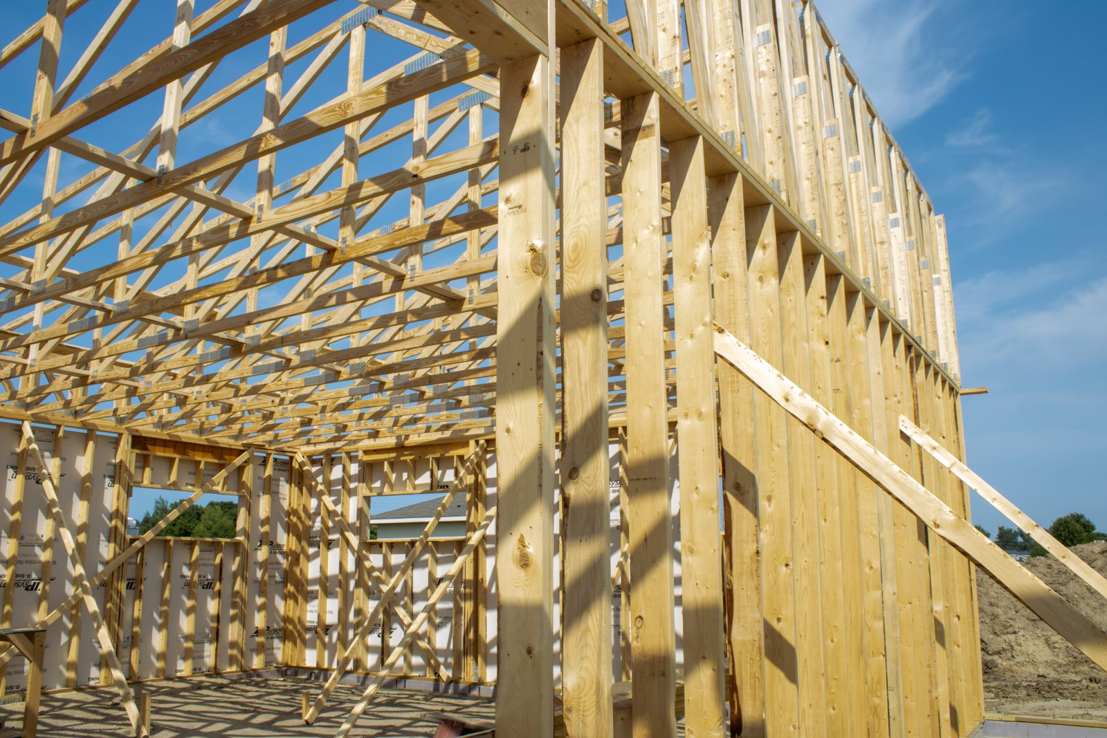 Wood framing of the new Dermatology Partners Owatonna clinic under a blue sky.
