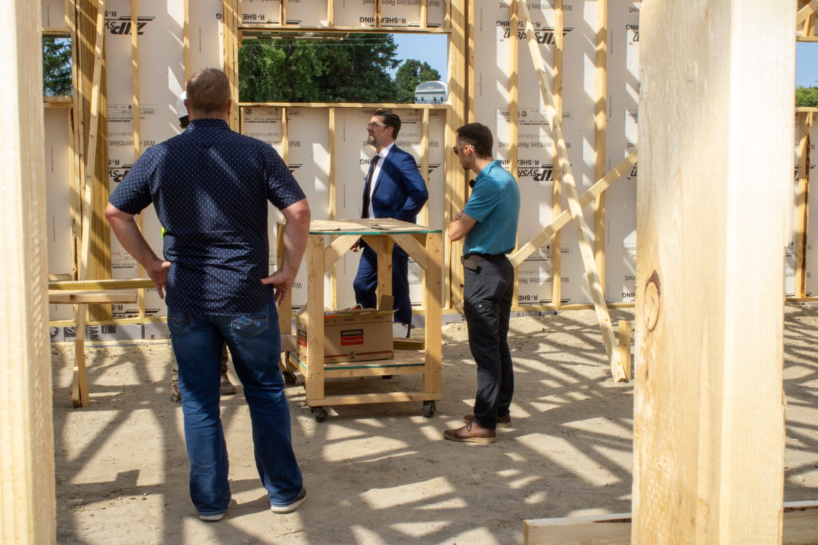 Three people standing inside the framed structure of the new clinic, discussing the layout.